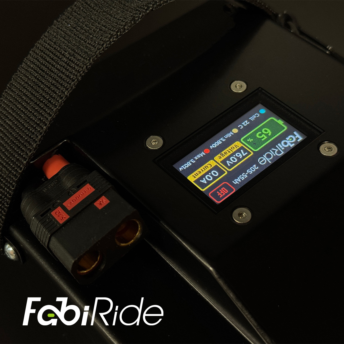 Juodas elektrinis krosinis motociklas su geltonais akcentais žalios sienos fone.